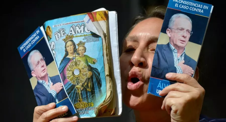 Mujer sostiene fotos de Uribe, quien saldría pronto de detención, según Dávila