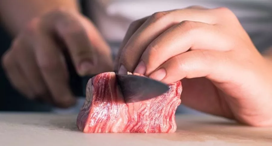 Personas corta pedazo de carne ilustra nota de mamá que obligó a su hija vegana a cocinar carne