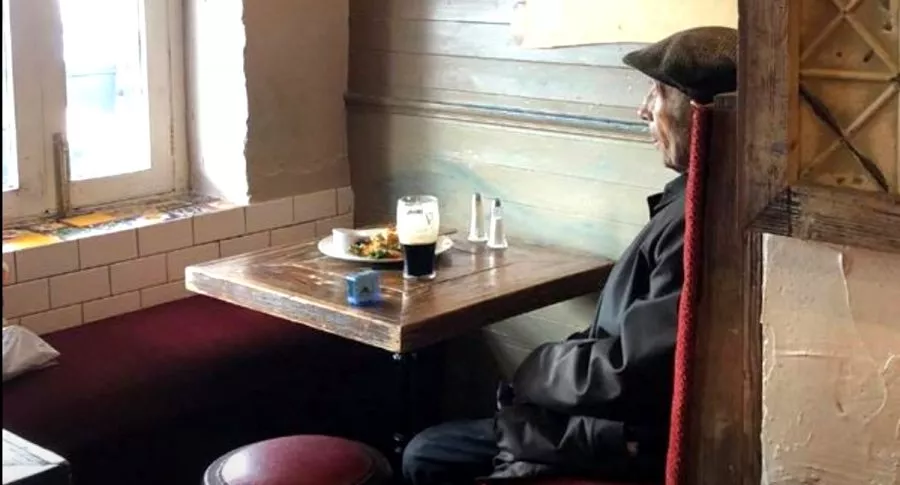 Adulto mayor toma cerveza en un pub irlandés.