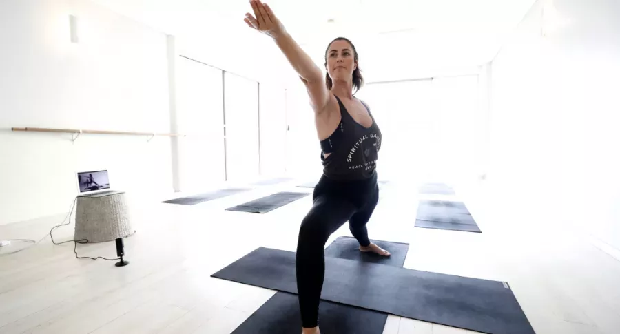 Mujer haciendo yoga en casa, ilustra nota de yoga para principiantes.