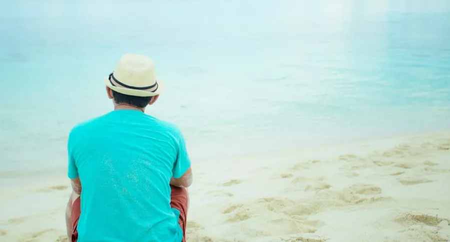 Imagen de un hombre sentado en una playa que ilustra la nota de un turista que fue multado por querer llevarse 2 kilos de arena de una playa en Italia.