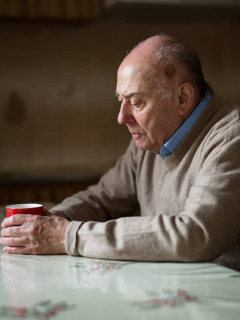 Imagen de adulto mayor sentado tomando café que ilustra nota sobre el posible aumento de la edad de pensión
