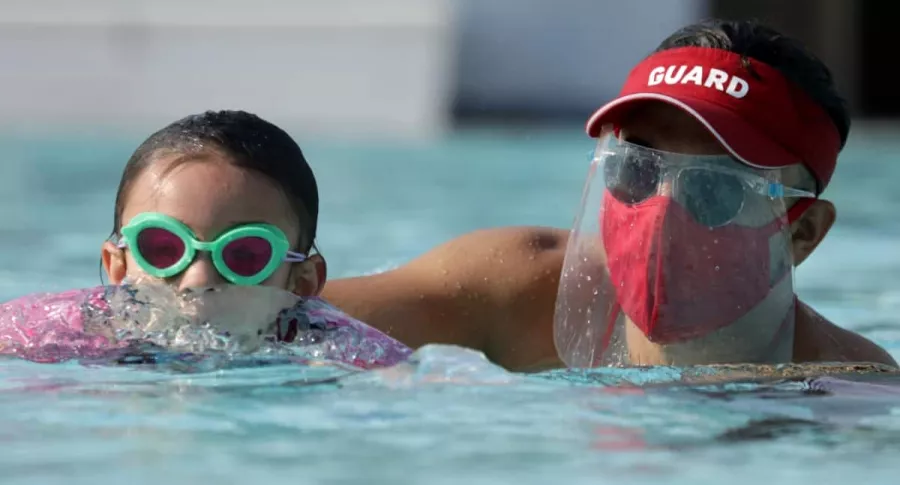 Salvavidas Michael Alfaro entrena con Kaila Holliday, de 5 años, en Los Ángeles, con protocolos de bioseguridad similares a los exigidos en Colombia para el uso de piscinas.