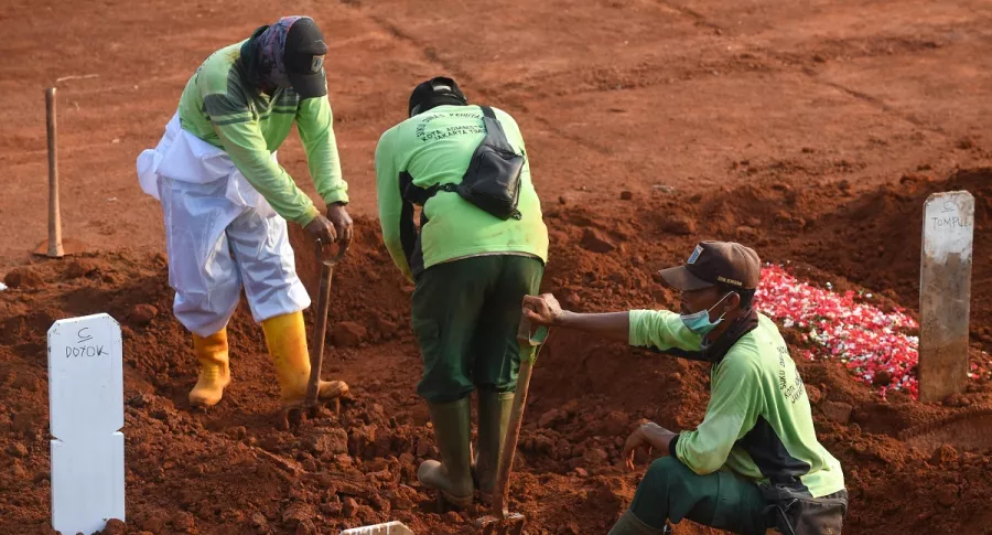Sepultureros cavando tumbas para los fallecidos por COVID-19 en indonesia.
