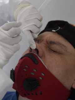 A health worker takes a swab from a man being tested for COVID-19 coronavirus pandemic after Bogota's Mayor Claudia Lopez, lifted the strict quarantine measure in some sectors of the city, in Bogota on August 27, 2020. (Photo by Raul ARBOLEDA / AFP)