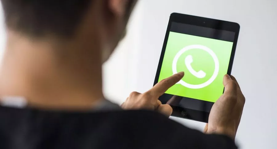 Hombre toca una pantalla que tiene el logotipo de WhatsApp con su dedo, nueva forma en la que se podrá iniciar sesión en WhatsApp Web
