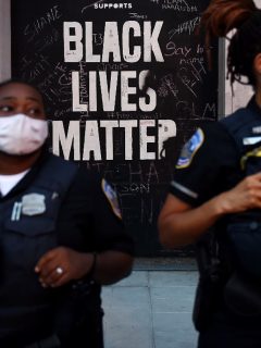 Letrero de Black Lives Matter detrás de policías de Nueva York.