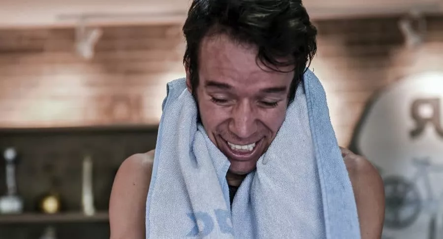 Colombian cyclist Rigoberto Uran of the Education First team wipes his sweat with a towel as he rides a stationary bike while racing with fans through a simulator as a training session at his office in Medellin, Colombia, on May 16, 2020, amid the new coronavirus pandemic. (Photo by JOAQUIN SARMIENTO / AFP)