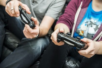 Dos personas con controles de consolas de videojuegos, los cuales, según una investigación, mejoran la memoria al ser adultos si se juegan en la infancia