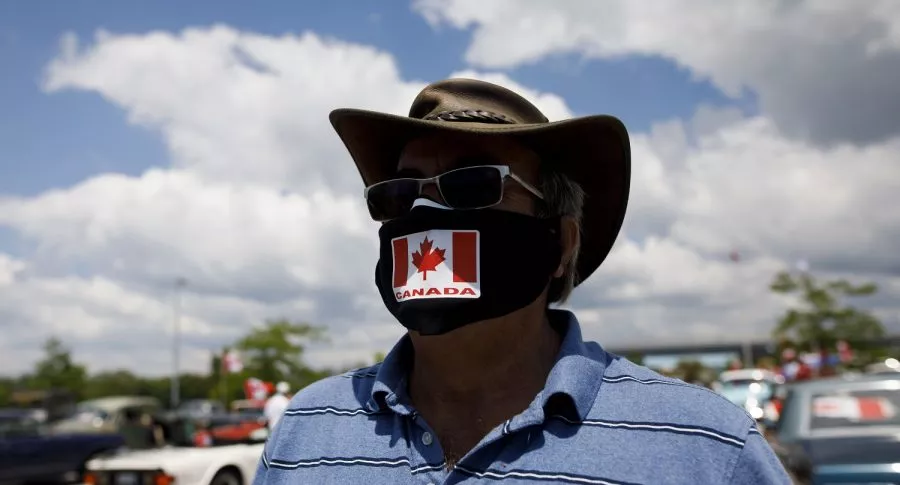 Imagen de hombre usando tapabocas con la bandera de Canadá ilustra nota sobre advertencia de rebrote de coronavirus en ese país