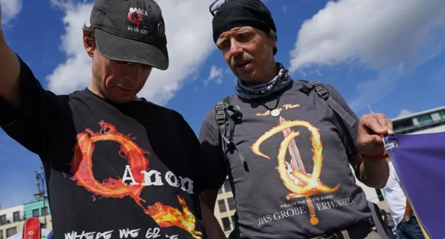 Dos estadounidenses lucen camisetas de Qnon, un movimiento conspirativo que endiosa a Donald Trump.