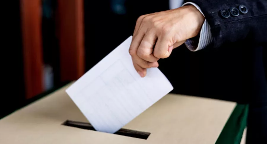 Persona deja su voto en una caja, ilustra nota de alcalde reelegido a pesar de estar muerto