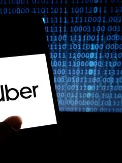 Celular con imagen de Uber y código binario. SIC reitera orden a Uber sobre protección de datos personales.