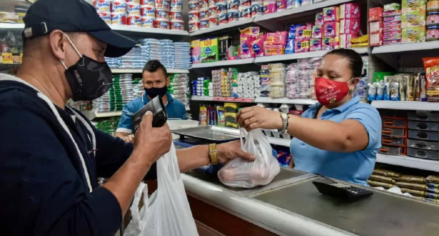 Colombiano haciendo compras en tienda de barrio: Gobierno define fecha de reforma tributaria y da pistas sobre si se moverá o no el IVA.