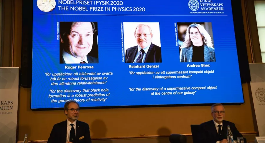 David Haviland (L), member of the Nobel Committee for Physics, and Goran K Hansson, Secretary General of the Academy of Sciences, sit in front of a screen displaying the winners of the 2020 Nobel Prize in Physics (L-R) Briton Roger Penrose, Reinhard Genzel of Germany  and Andrea Ghez of the US, during a press conference at the Royal Swedish Academy of Sciences, in Stockholm, on October 6, 2020. - Roger Penrose of Britain, Reinhard Genzel of Germany and Andrea Ghez of the US won the Nobel Physics Prize on Tuesday for their research into black holes, the Nobel jury said. (Photo by Fredrik SANDBERG / TT NEWS AGENCY / AFP) / Sweden OUT