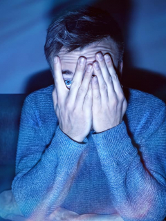 Hombre asustado viendo películas de terror, que son muy comunes en Halloween para ver en Netflix, HBO y Amazon Prime