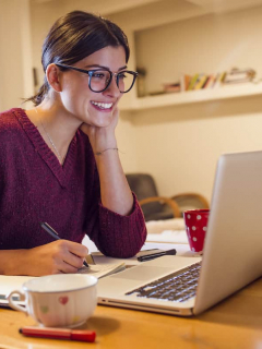 Imagen de mujer sonriendo mientras ve su computador para ilustrar nota sobre qué foto se debe usar en LinkedIn para buscar empleo