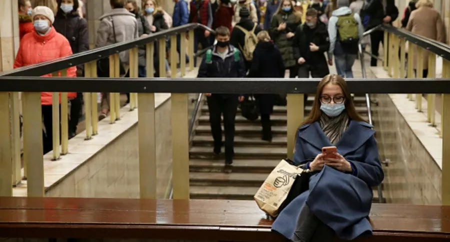 Personas con tapabocas en una estación de metro, ilustra nota de advertencia de OMS sobre pandemia lejos de acabarse