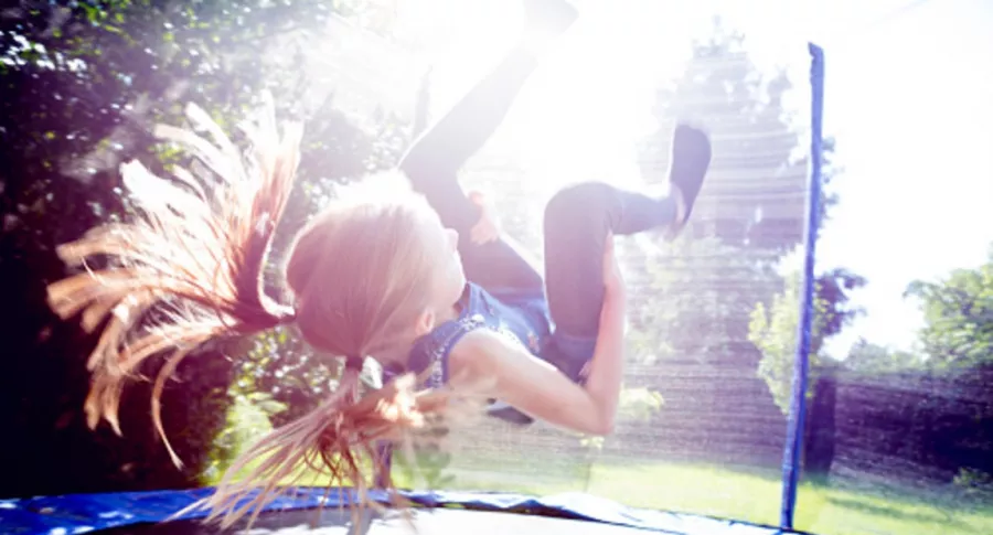 Imagen de niña saltando en trampolín bajo el sol