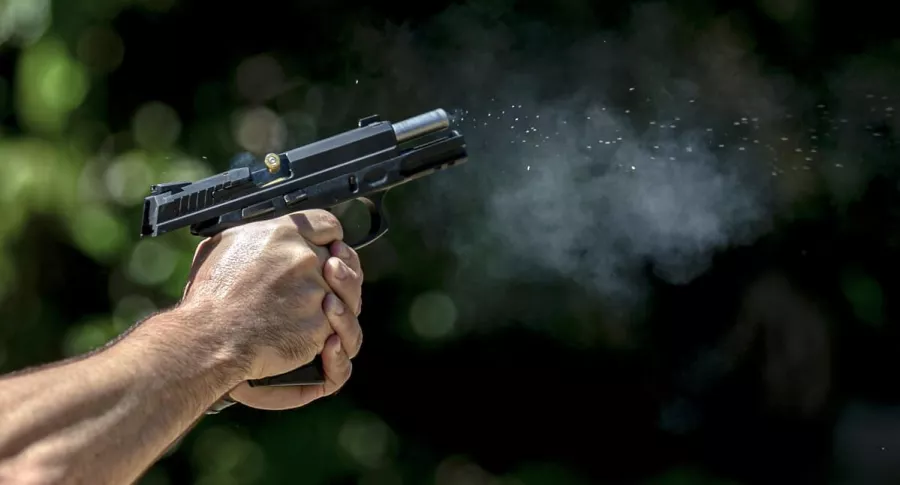 Hombre que dispara pistola ilustra artículo Vigilante fue asesinada en tiroteo entre fleteros y expolicía