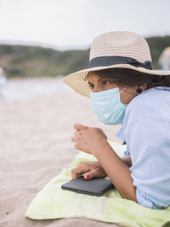 Mujer en la playa con tapabocas para ilustrar nota sobre el contagio de COVID-19 en el mar y en las piscinas