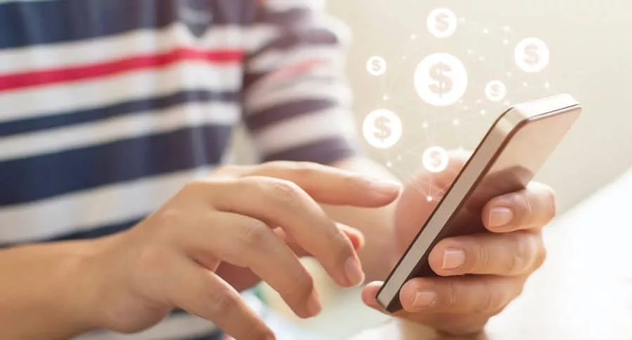 Persona con celular en las manos y signos de dinero para ilustrar nota sobre aplicaciones para ganar dinero