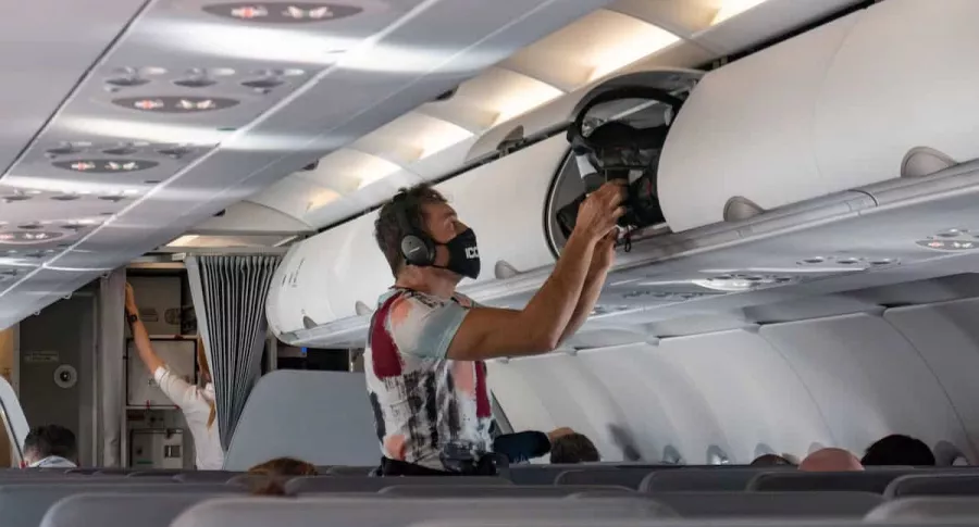 Pasajero de avión usando tapabocas para ilustrar nota sobre estudio que dice que viajar en avión es más seguro que salir a comer