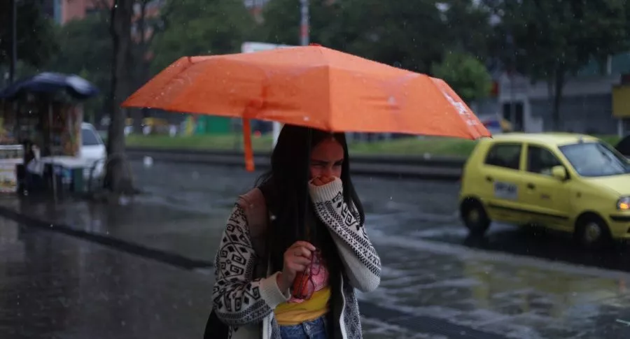 Joven con sombrilla en Bogotá, ilustra nota sobre localidades que se verán más afectadas por las lluvias esta semana