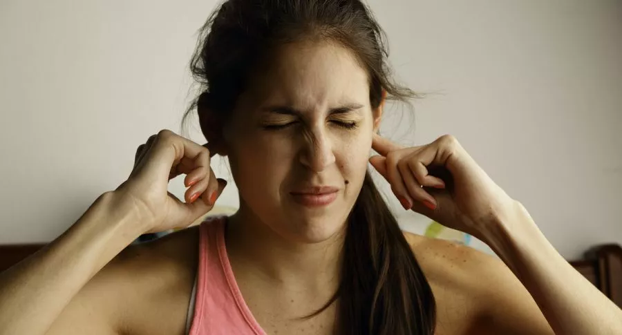 Mujer con molestia en los oídos para ilustrar nota sobre el impacto de la COVID-19 en el tinnitus
