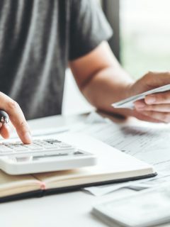 Persona usando calculadora para ilustrar nota sobre créditos con menos intereses