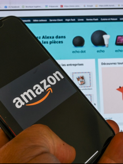 Imagen de persona que posa con un celular que muestra el logotipo de Amazon, frente a una pantalla de computador, ilustra artículo Farmacia digital de Amazon hace temer fin de droguerías.