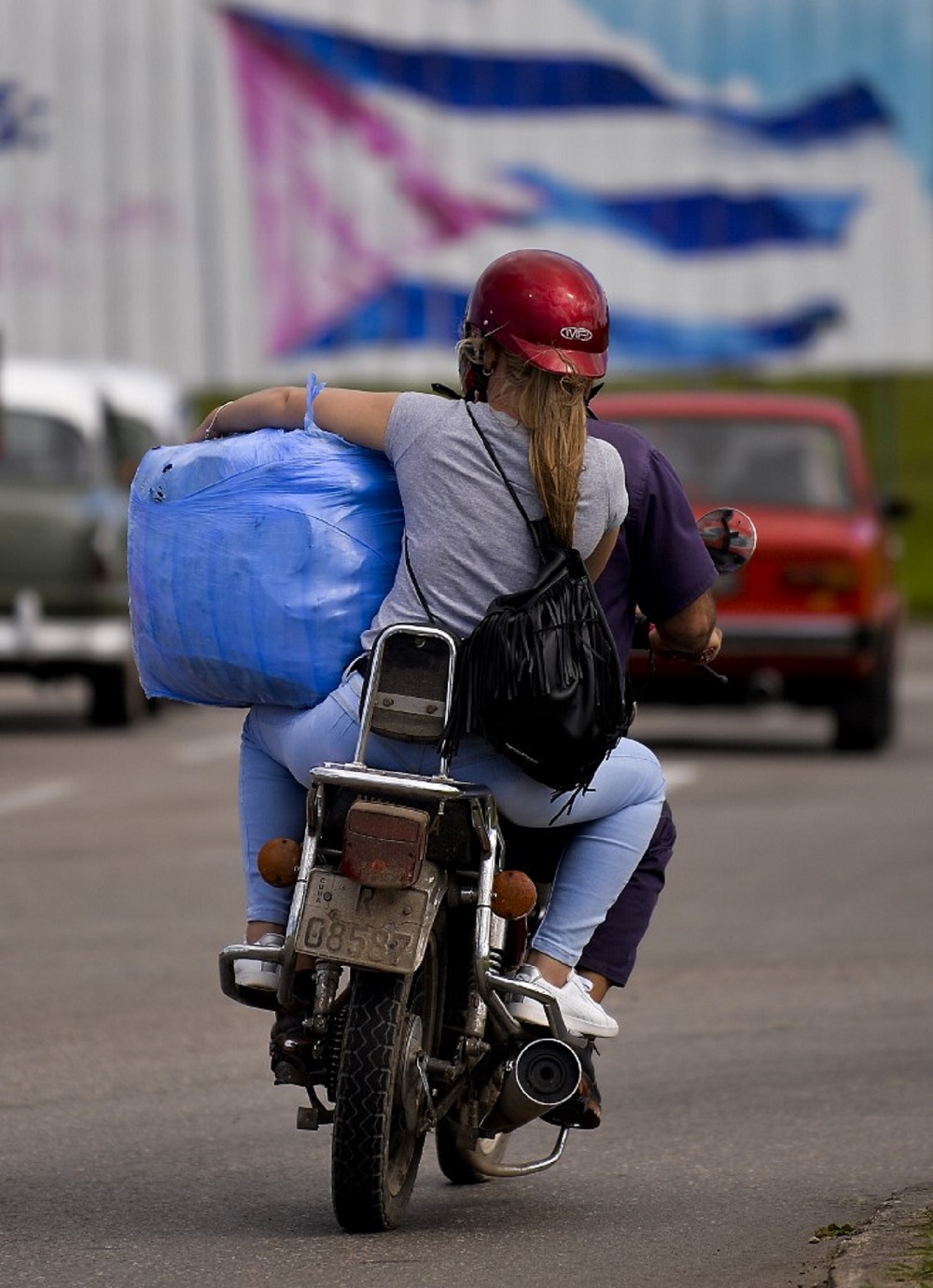 Una mujer carga un paquete cuando sale del aeropuerto José Martí, de La Habana, en una motocicleta. Los cubanos reactivaron su arcaico pero eficiente sistema de mulas / AFP. 

