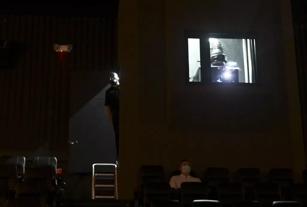 Uno de los operadores de una cabina de proyección mira el vacío de la sala antes del inicio de una película / AFP.

