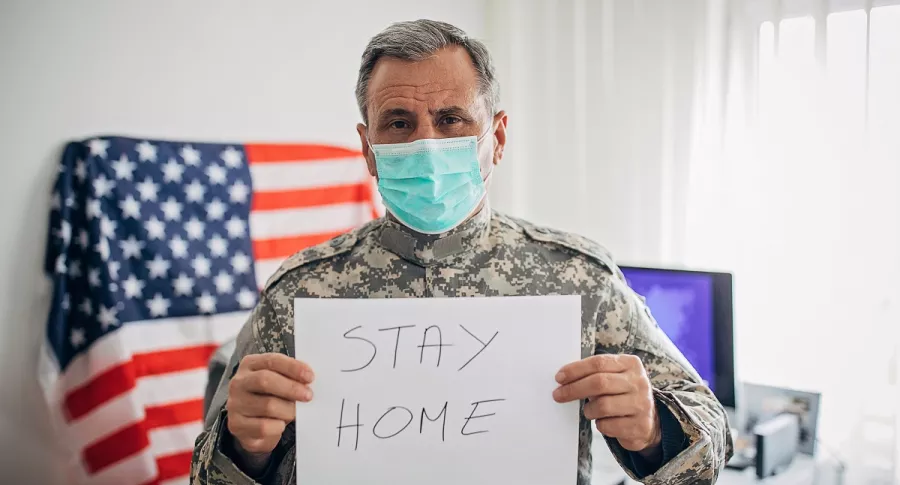 Militar estadounidense sosteniendo papel con mensaje “quédate en casa”, a propósito de la explosión de coronavirus que Estados Unidos viviría en diciembre.