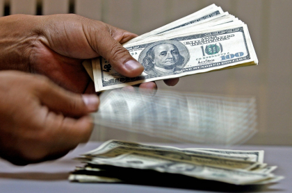 Imagen de persona manipulando dólares ilustra artículo Coronavirus disparó riqueza de multimillonarios de EE.UU.