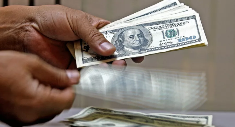 Imagen de persona manipulando dólares ilustra artículo Coronavirus disparó riqueza de multimillonarios de EE.UU.