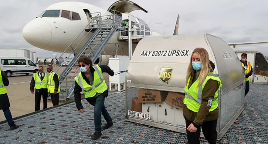 Empleados de UPS transportan cargamento de dosis de la vacuna.