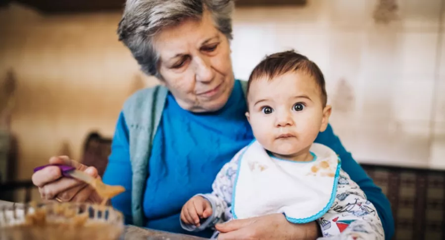 Abuela da de comer a bebé, ilustra foto de mujer que le cobra a su hija por cuidar a si nieto