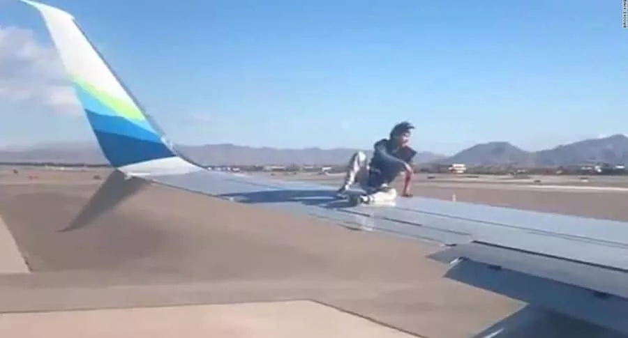 Captura de pantalla de video de un hombre que se subió al ala de un avión que iba a despegar y luego se cayó al suelo