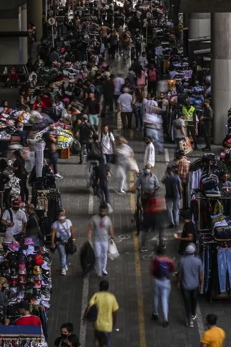 La gente camina mientras los vendedores ambulantes interactúan con los clientes en medio de la pandemia, en una calle de Medellín / AFP. 