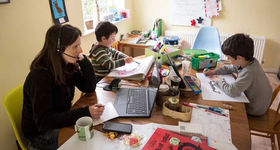 Imagen de mujer trabajando al lado de sus hijos ilustra artículo Teletrabajo: riesgo de borrar frontera trabajo-vida privada
