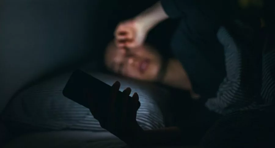 Mujer con celular en la noche, ilustra nota de policía que mandó a dormir a mujer que llamó a denunciar fiesta ilegal