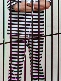 Imagen de hombre con traje de rayas detrás de una rejas ilustra artículo Cadena perpetua para violadores de niños podría caerse por un vicio