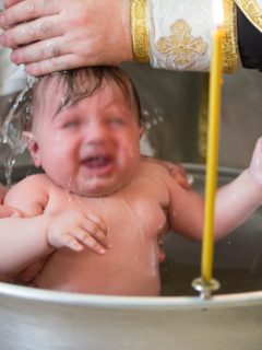 Niño siendo bautizado, ilustra nota de conmoción en Rumania por muerte de bebé durante bautismo