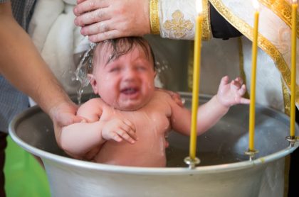 Niño siendo bautizado, ilustra nota de conmoción en Rumania por muerte de bebé durante bautismo