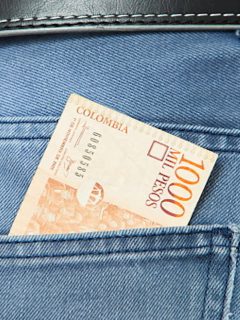 Billete de mil pesos en un bolsillo.