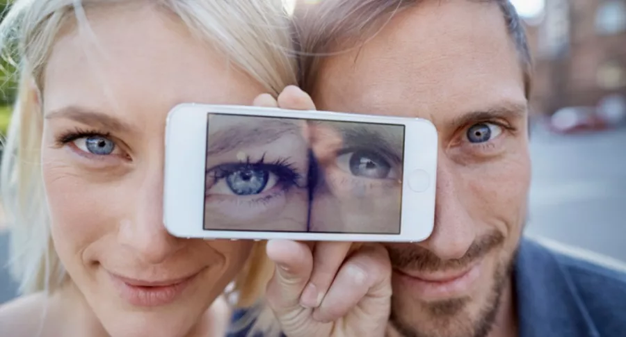 Hombre y mujer con celular en los ojos, ilustra nota de nuevo reto viral de ilusión óptica: ¿Cuántos colores ve?