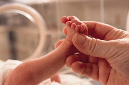 Imagen de pie de bebé recién nacido, agarrada por adulto, ilustra nota de doctor vende a bebé porque padres no podían pagar factura médica
