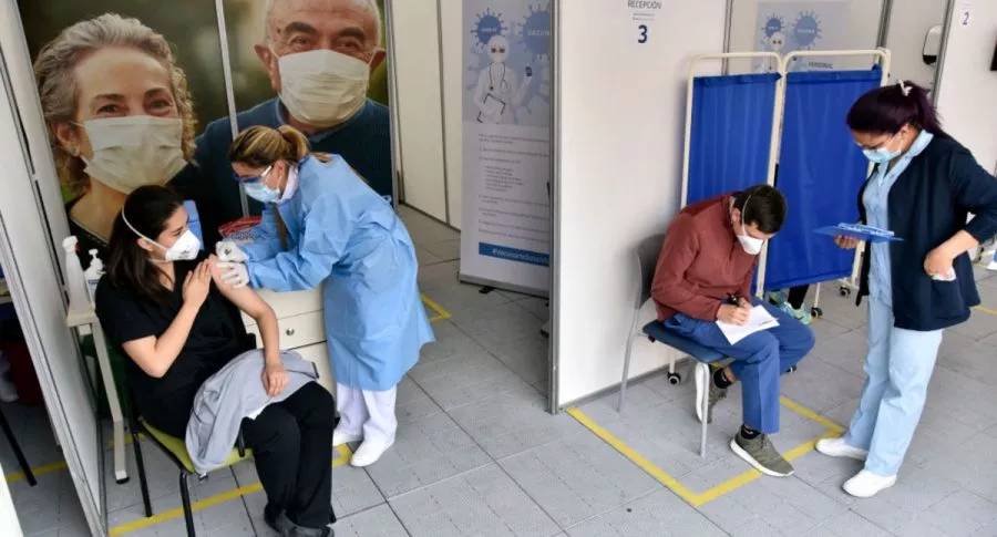 Enfermera vacuna a médico en Bogotá, ilustra nota de OMS dice que baja en casos de coronavirus aún no se debe a vacunación
