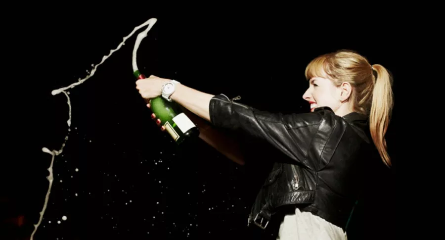 Mujer celebra destapando botella de champaña, ilustra nota de joven que mintió para no ir a trabajar y le envía por error foto con champaña